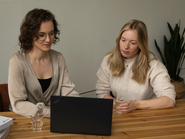 Tarieven bekijken Act en Adem Twee mensen bekijken samen een laptop, de een met een kopje in de hand.